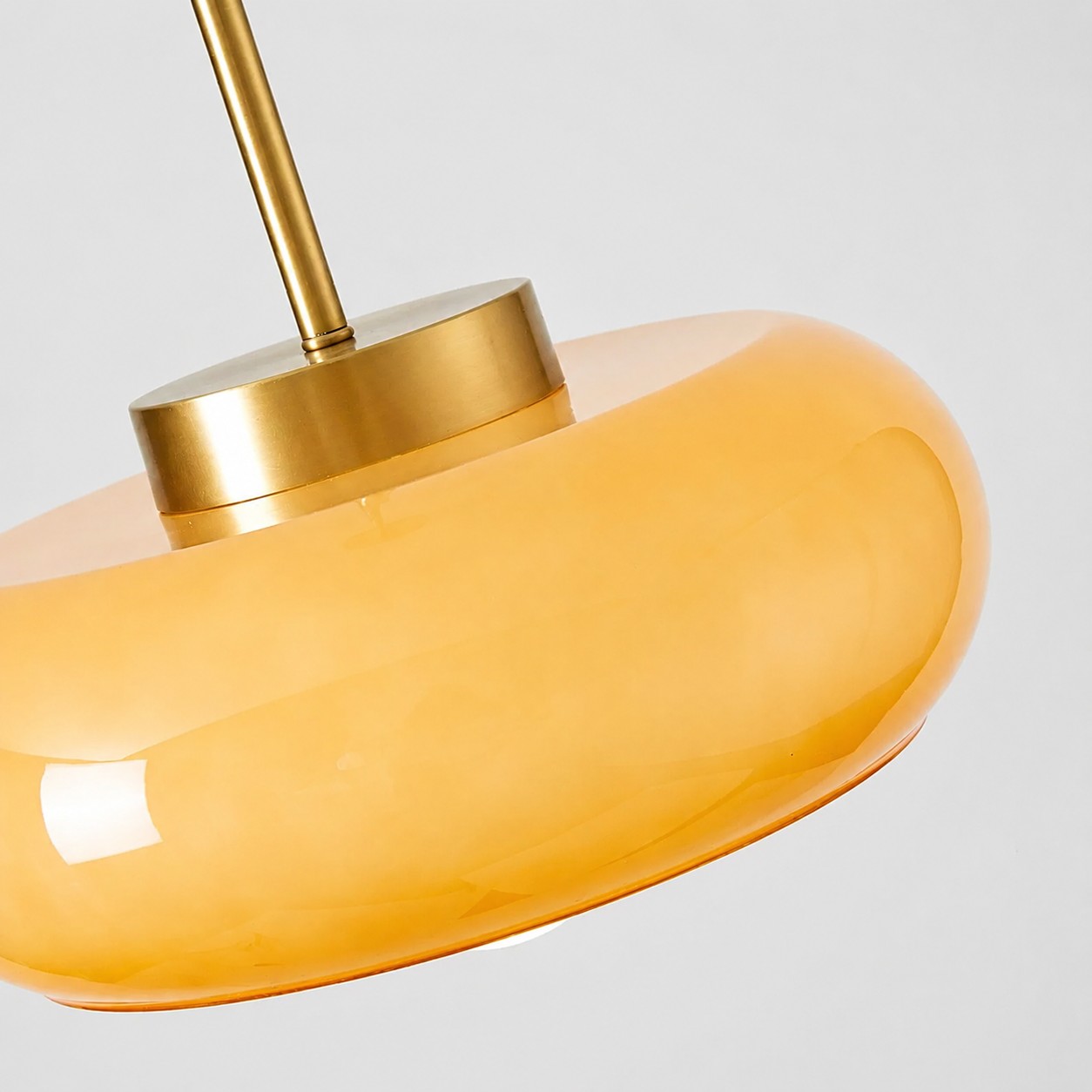 Detail van de oranje glazen kap en messing afwerking