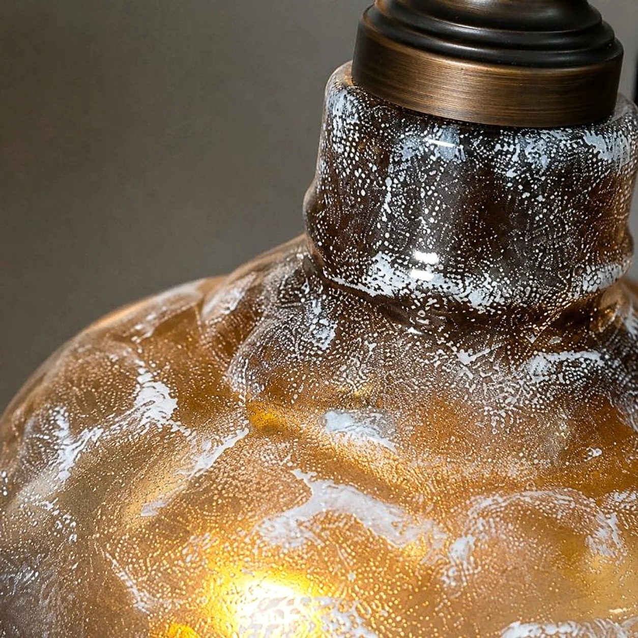 Close detail of smoky gray textured glass shade with warm amber tone