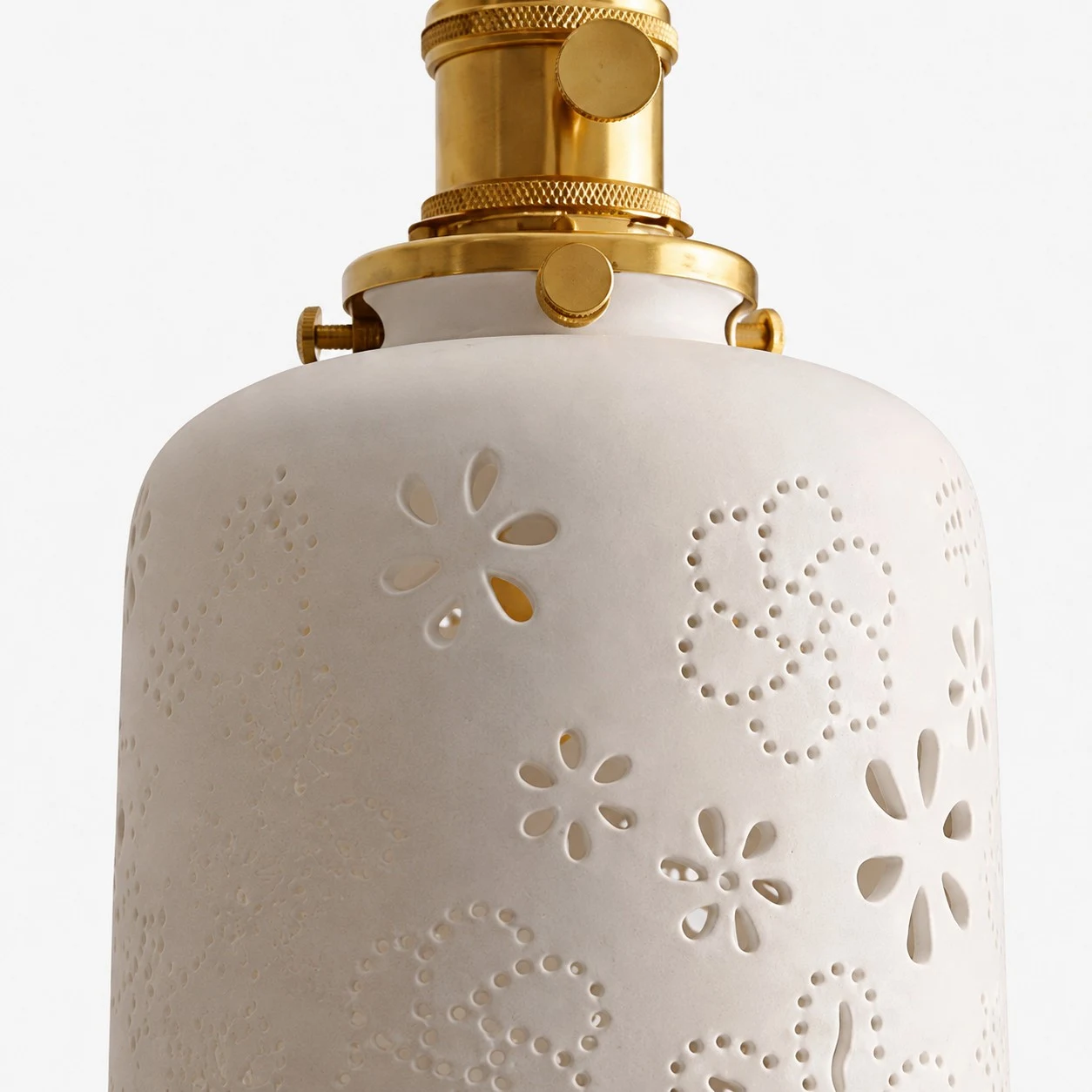 Close view of white ceramic shade with cutout floral pattern