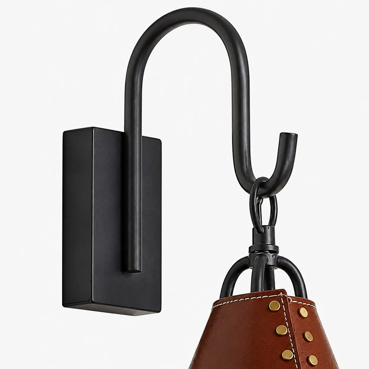 Close view of black rectangular wall plate and curved hook above the red shade