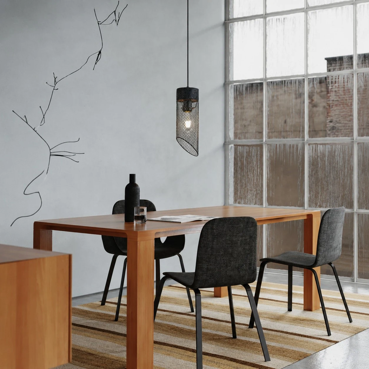 Black mesh stone pendant light over a dining table near a window