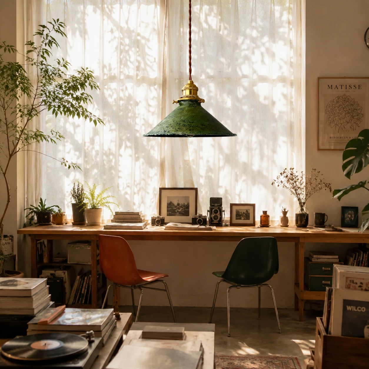 Distressed green pendant lamp over a warm studio worktable