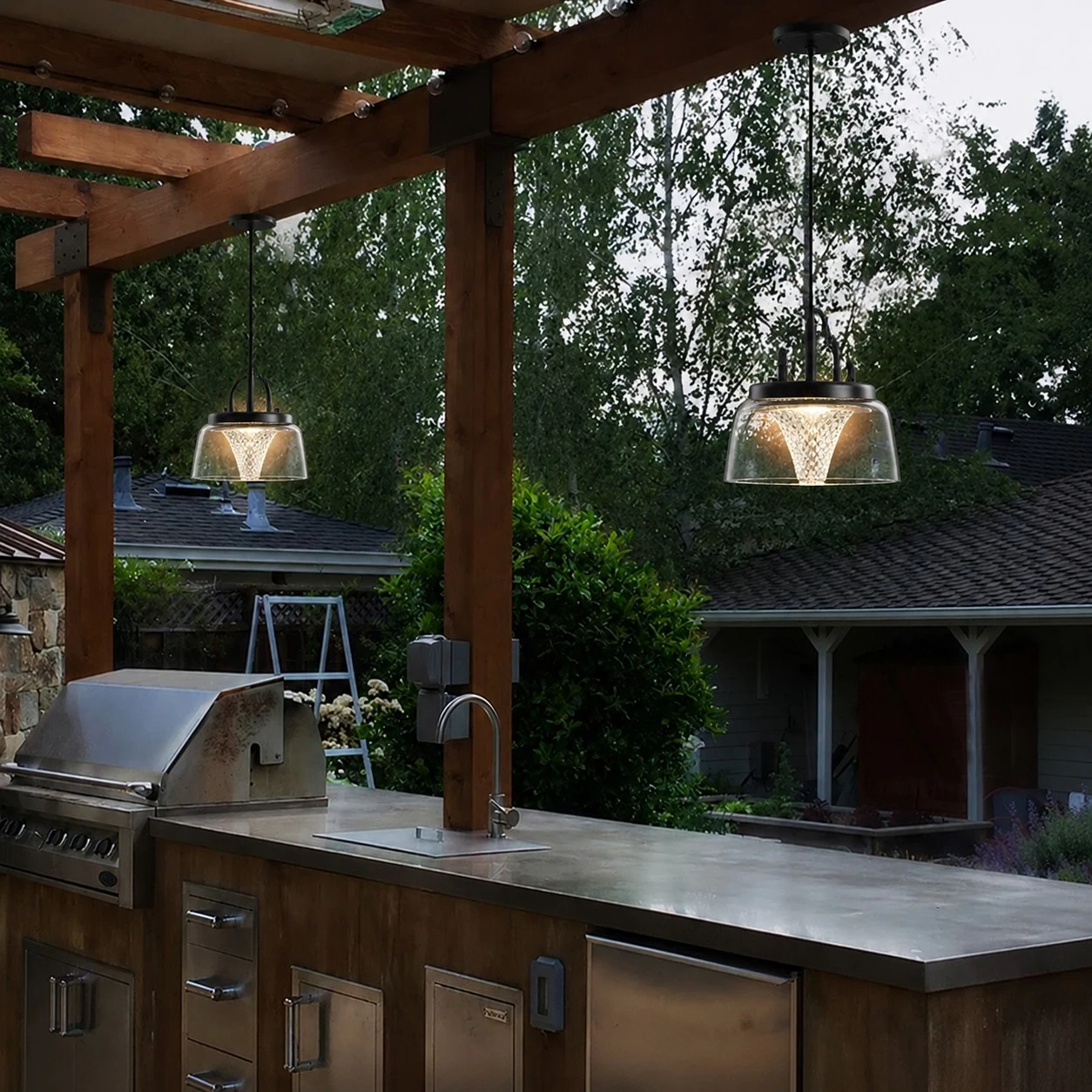 Clear solar pendant lanterns above an outdoor kitchen counter