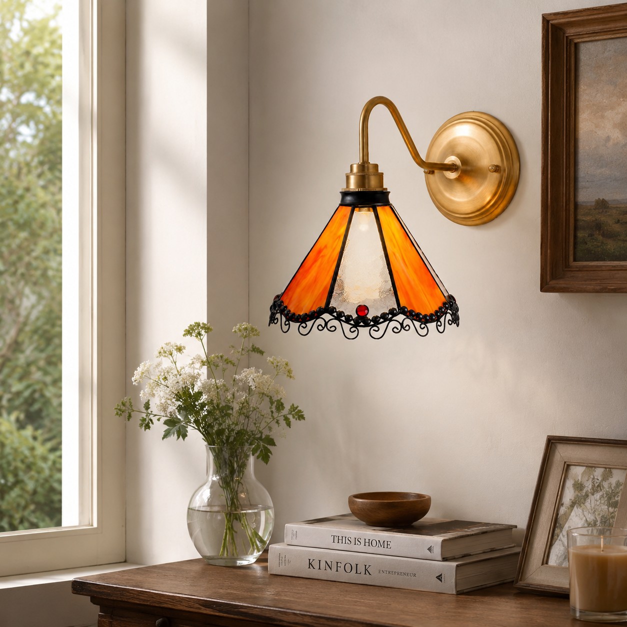 Orange stained glass wall sconce above a window console