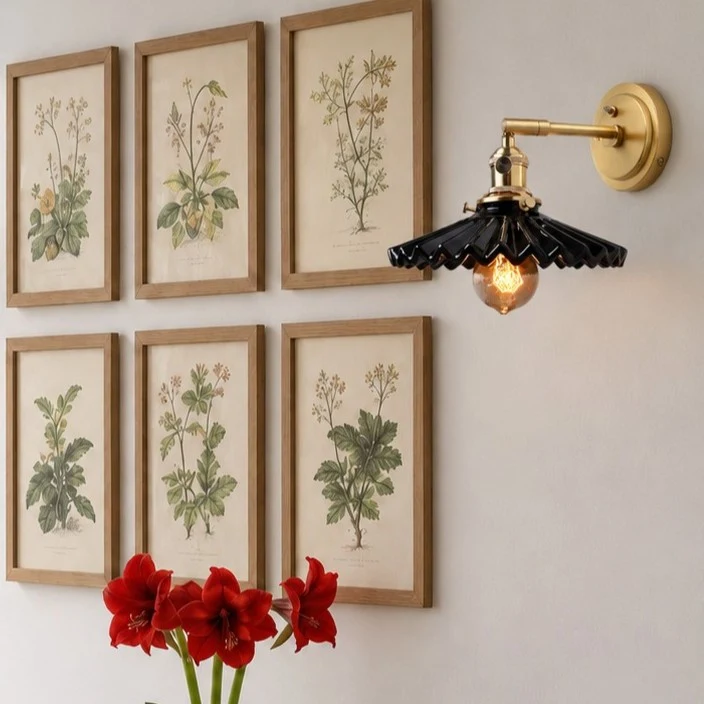 Black wall sconce above framed botanical art
