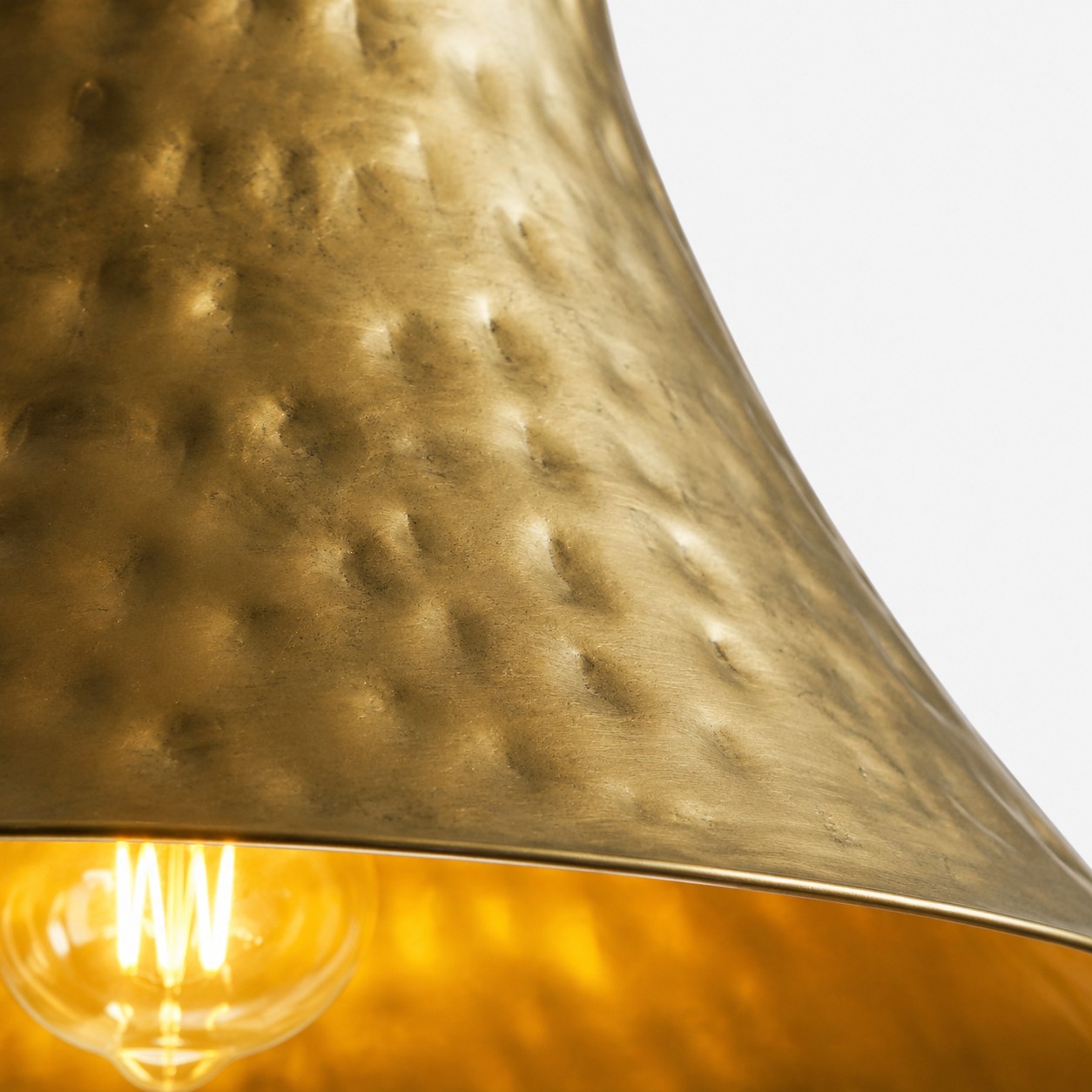 Close-up of hammered brass texture and warm bulb glow