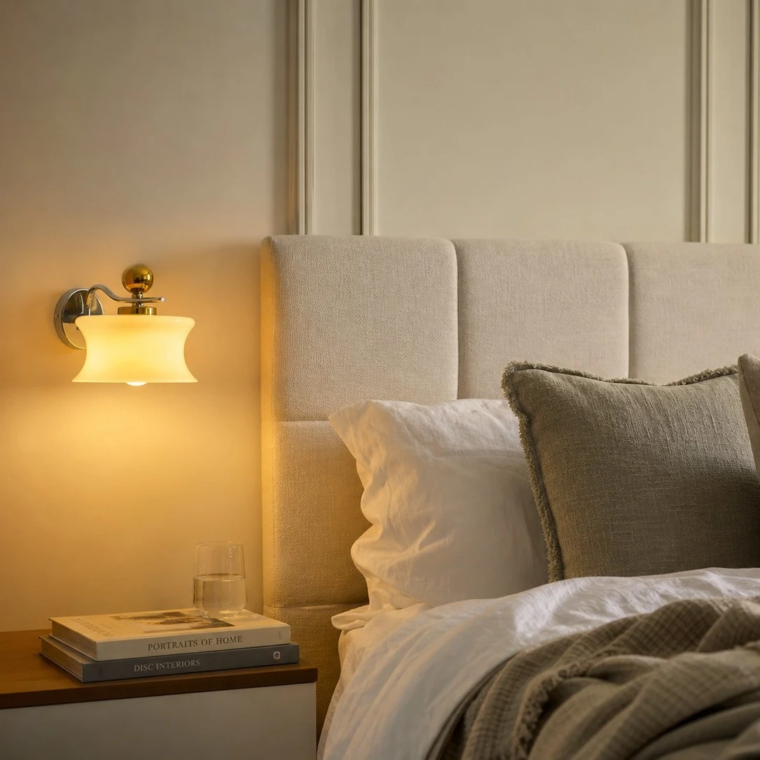 Cream glass wall lamp casting warm bedside light