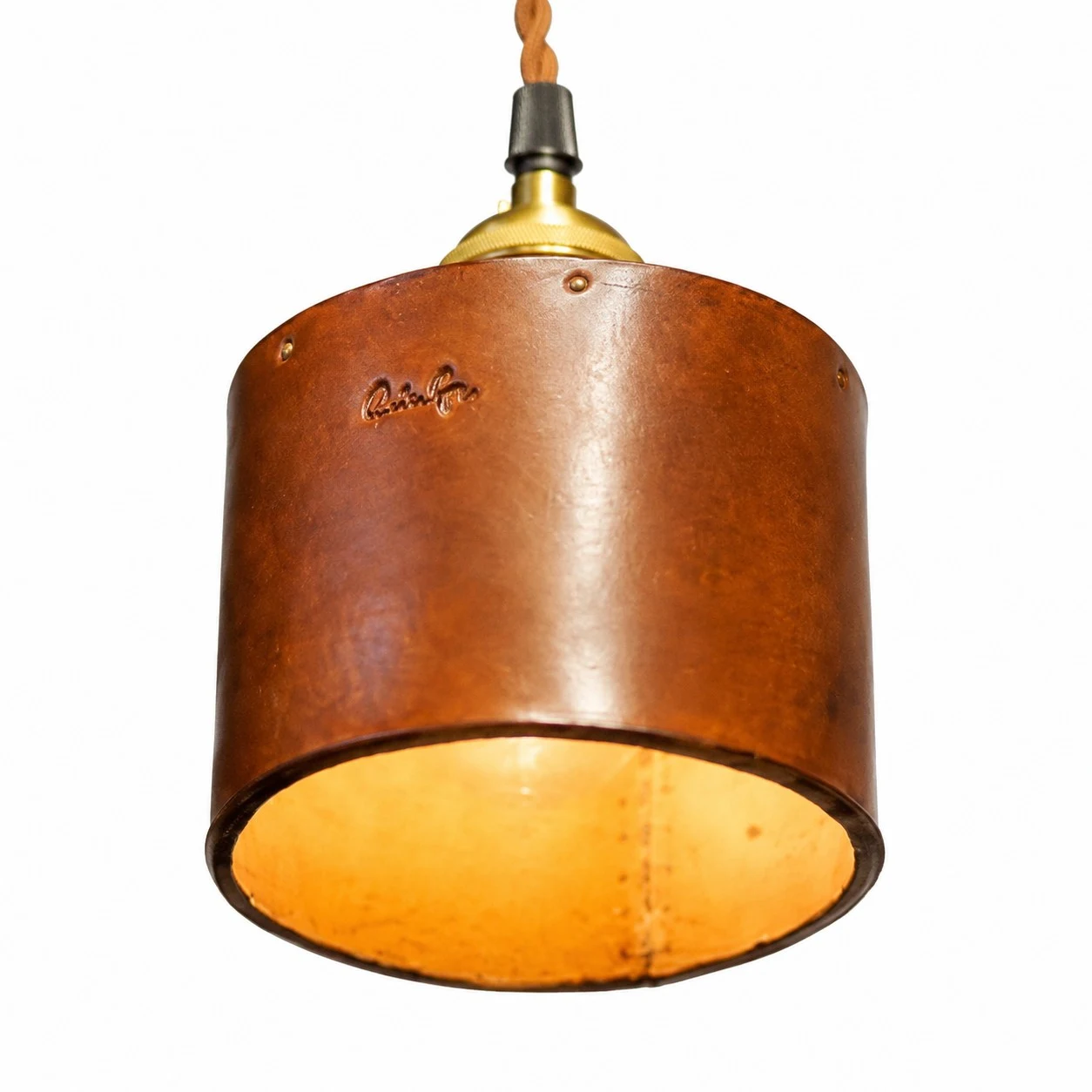 Close-up of brown leather cylinder shade with warm inner glow