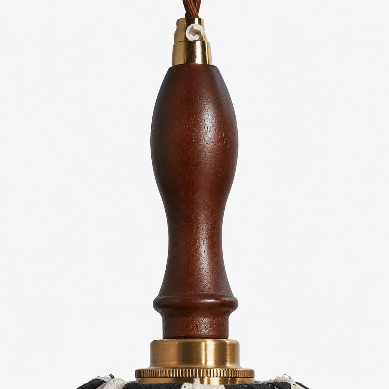 Close-up of dark wood handle, twisted cord and brass connector on the pendant lamp