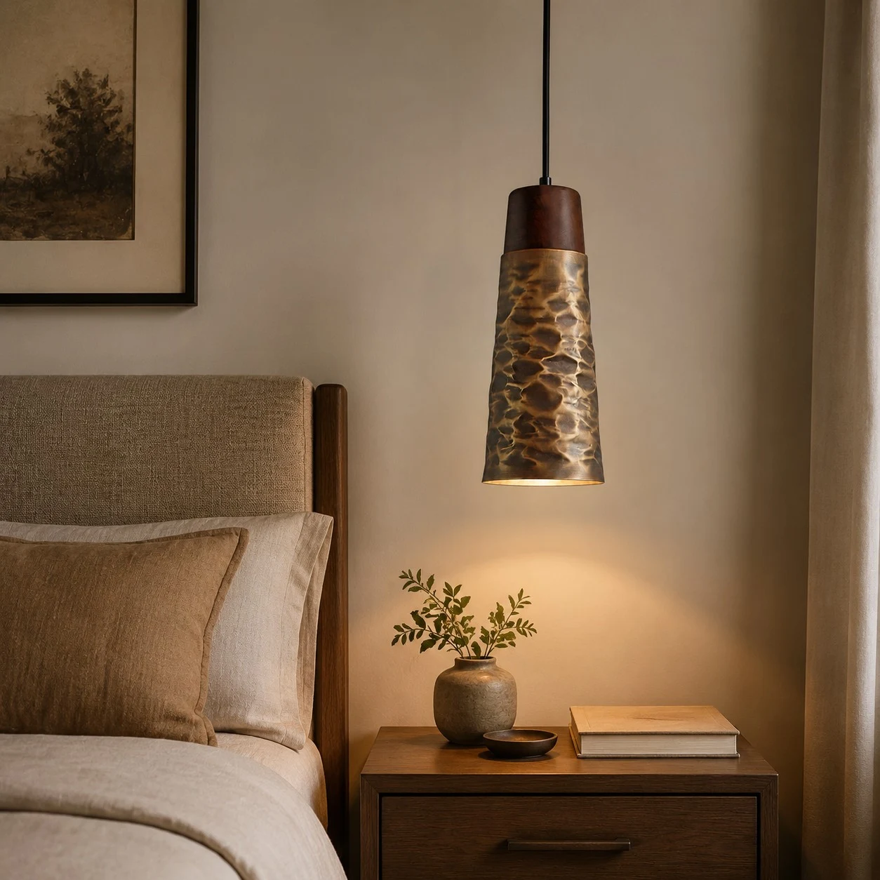 Single hammered copper pendant light beside a bed