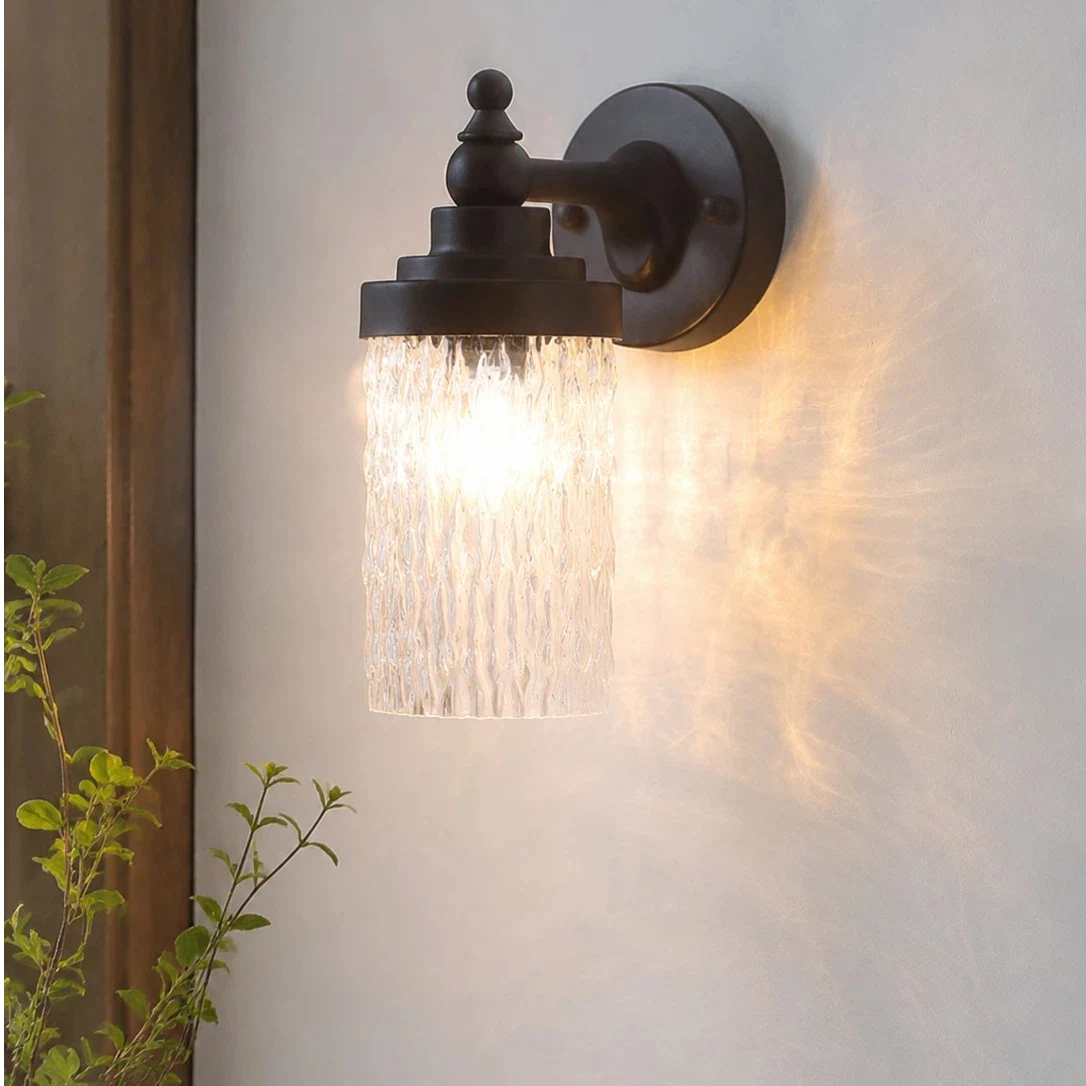 Averra matte black wall sconce casting warm light near an entryway