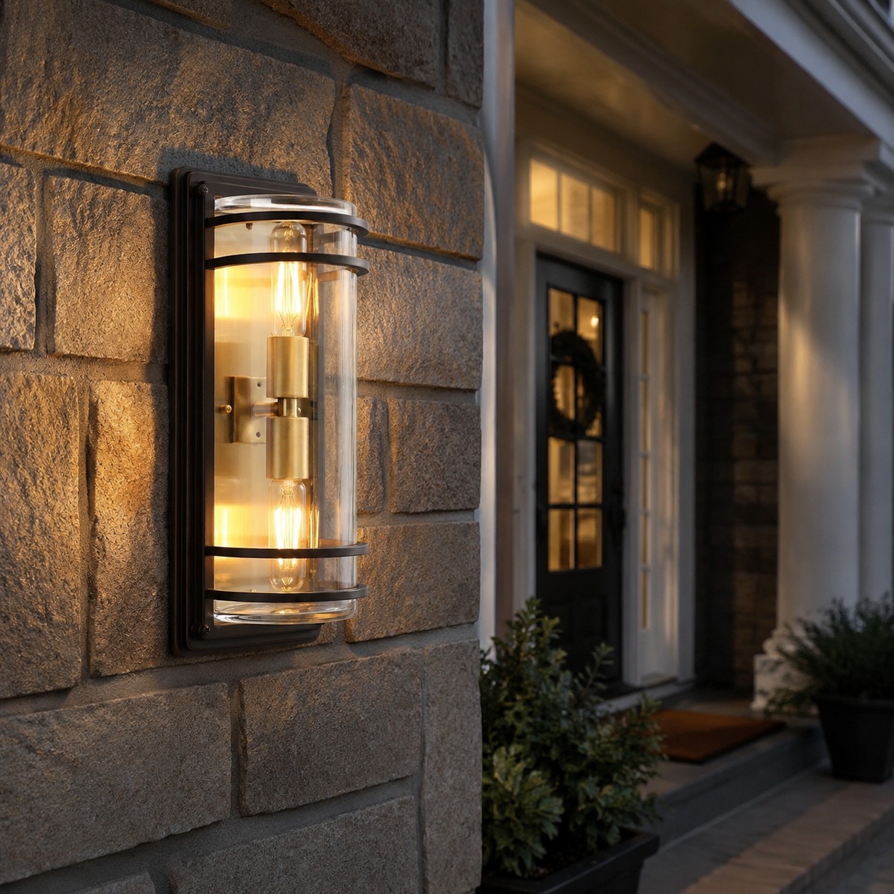 Medium bronze glass outdoor wall sconce glowing on a stone exterior wall