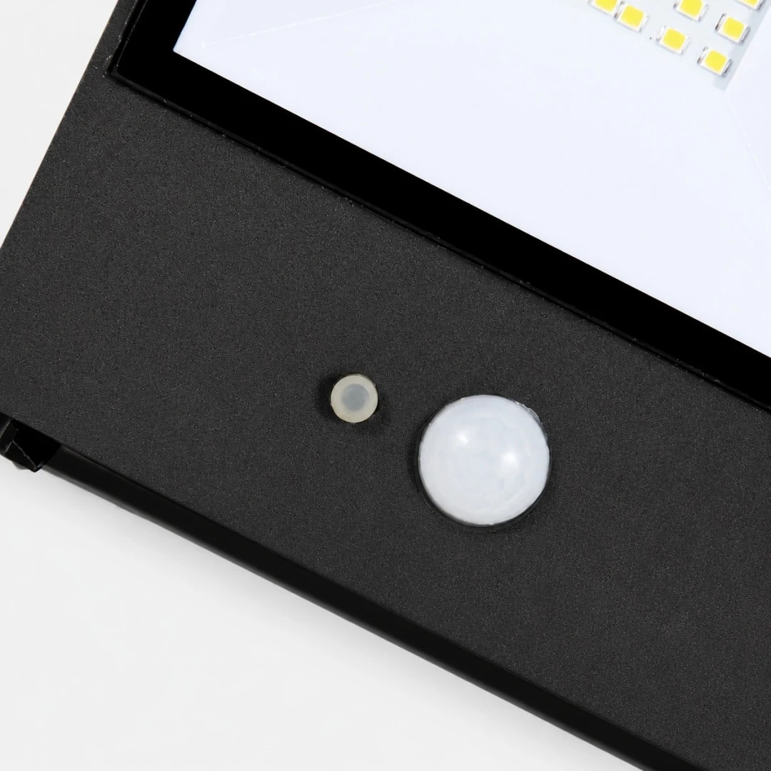 Close view of motion sensor and glass diffuser on black outdoor wall lamp