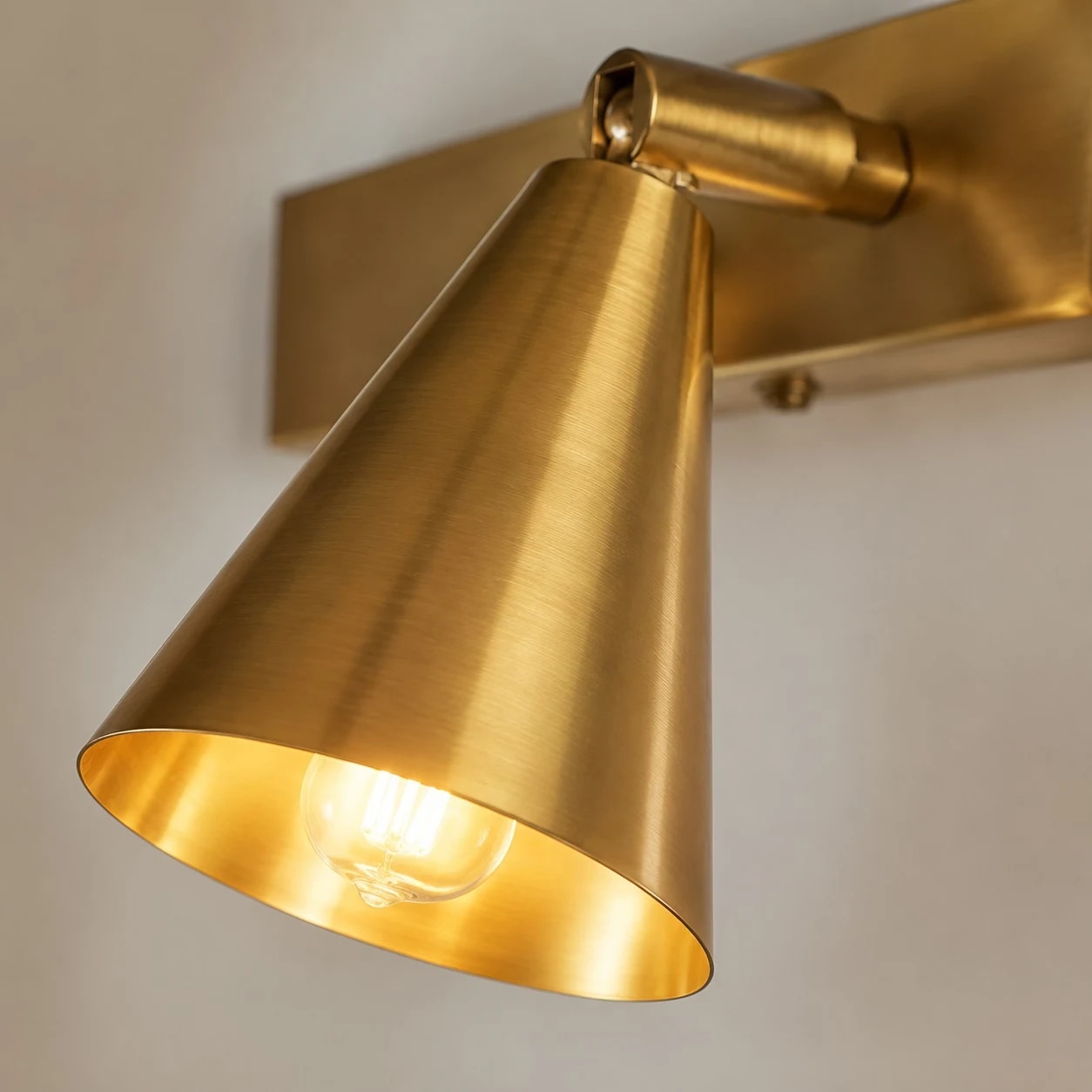 Close detail of lit brass cone shade and wall bracket