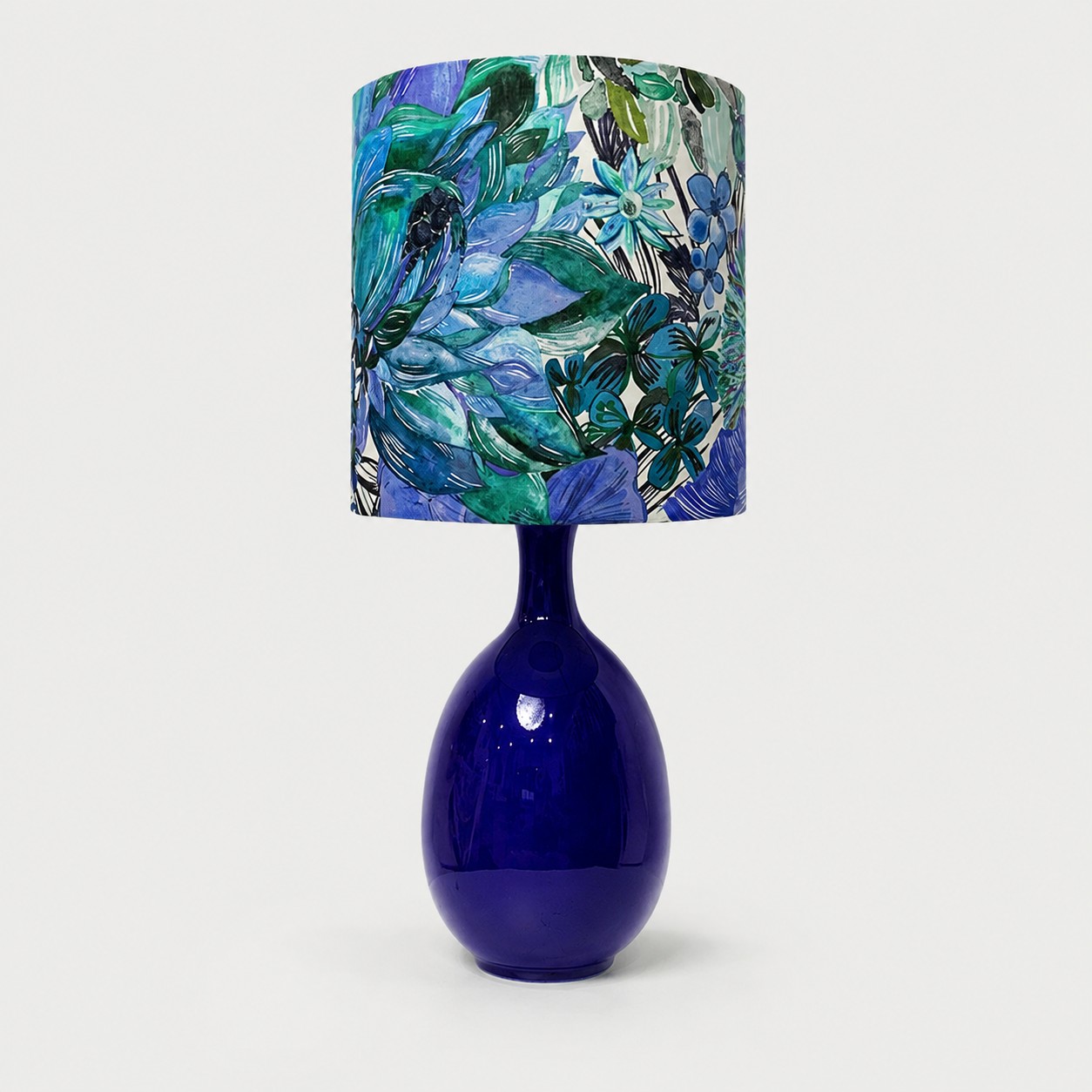 Green botanical fabric ceramic table lamp on plain background