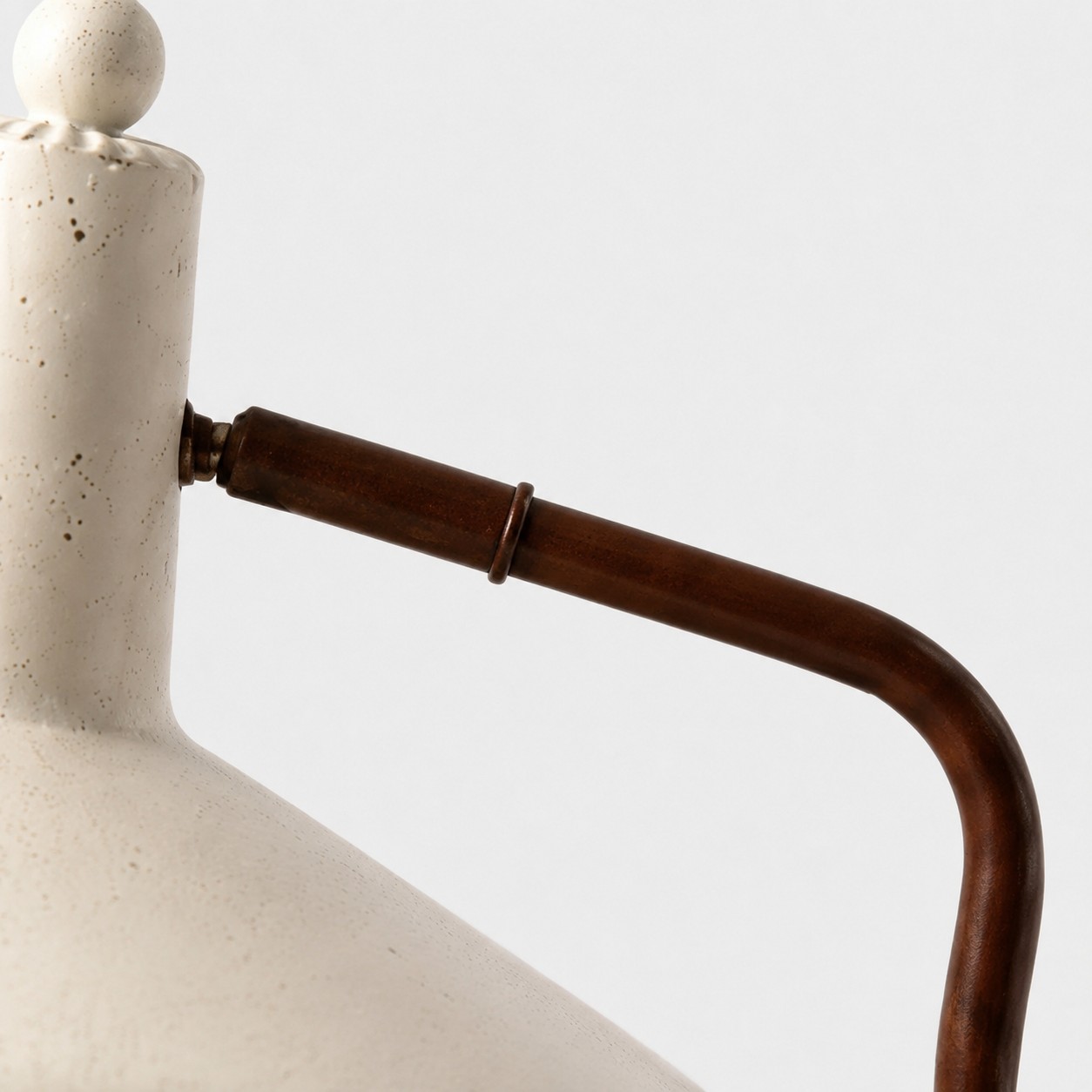 Close-up of curved brown iron arm and shade connection